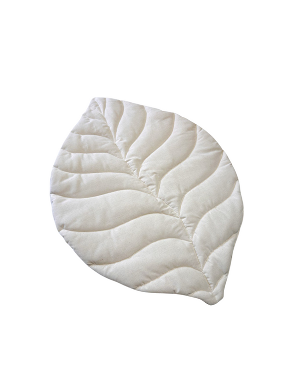 White linen leaf-shaped baby play mat on neutral nursery floor
