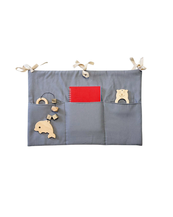 Gray linen crib toy pocket with three compartments, tied to a crib rail Linen toy pocket | Gray hellolittlefox linen-toy-pocket-gray hellolittlefox.myshopify.com