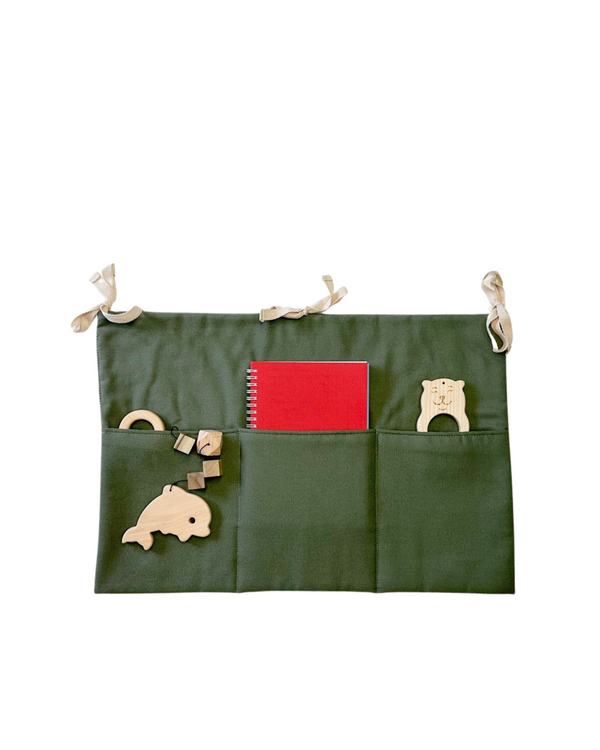 Khaki linen toy pocket with three compartments, hanging neatly on a baby crib
