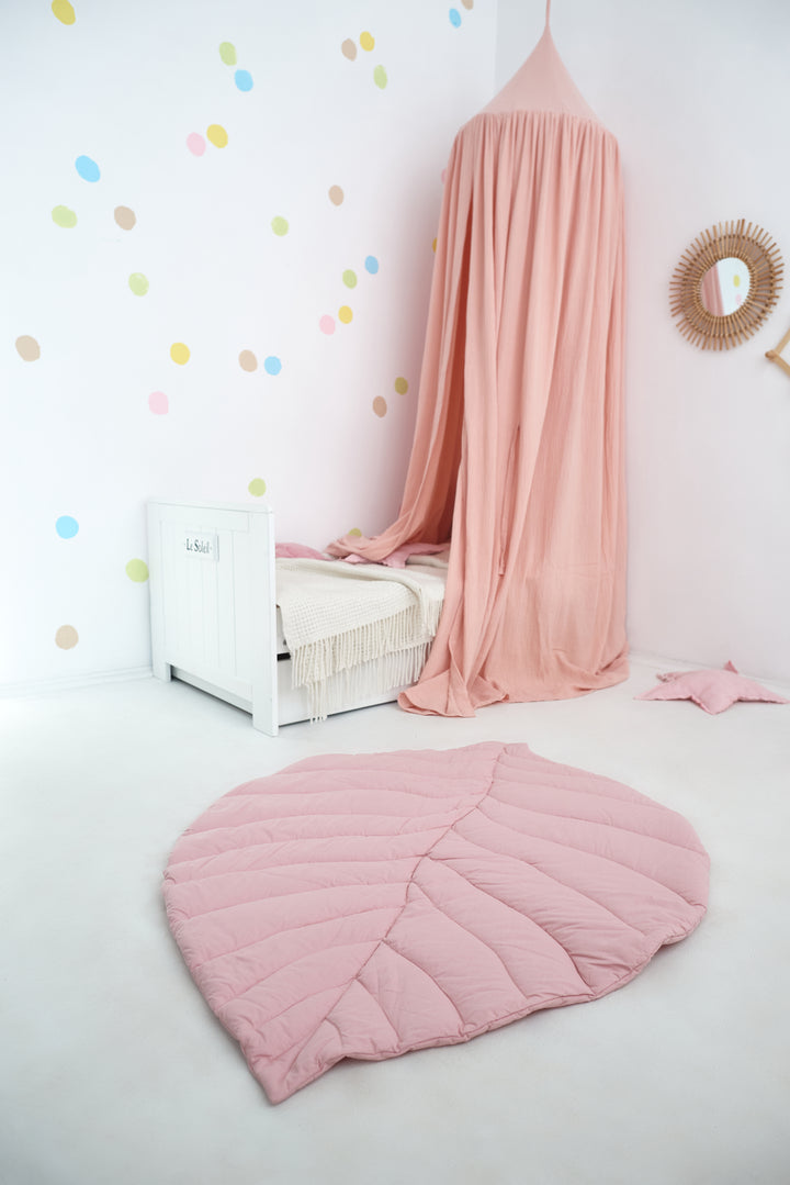 A cozy child’s bedroom with a pink canopy hanging above a small bed