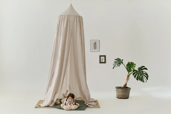 Checkered fabric bed canopy styled in a modern nursery