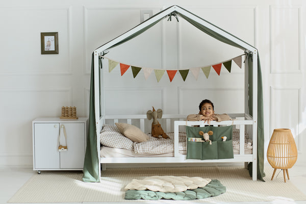 Breathable khaki bed curtains tied to the frame of a toddler bed