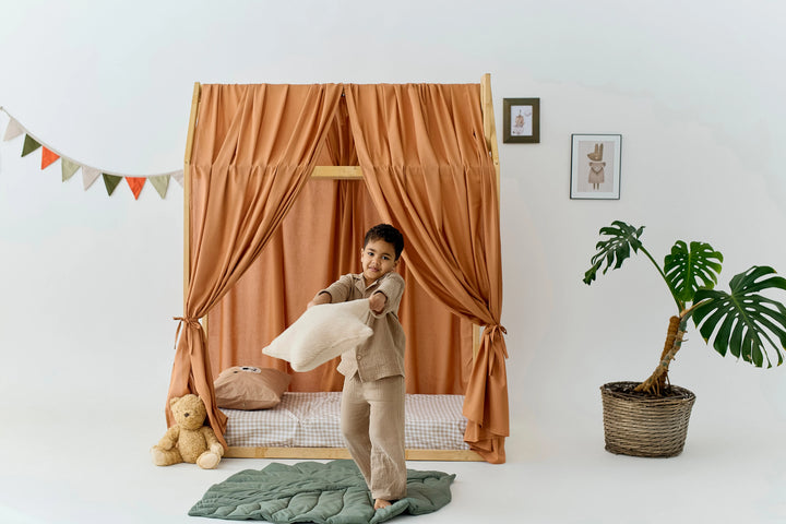 A young child is playfully holding a pillow in a cozy bedroom