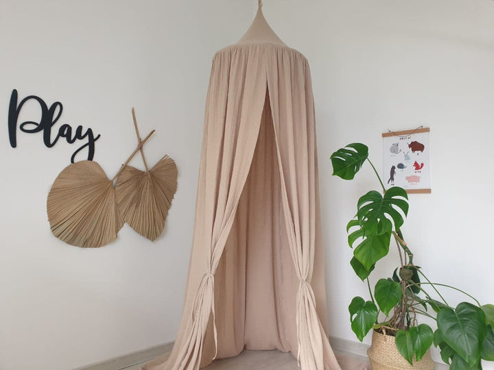 A Beige muslin canopy draped elegantly over a bed, creating a serene and dreamy atmosphere