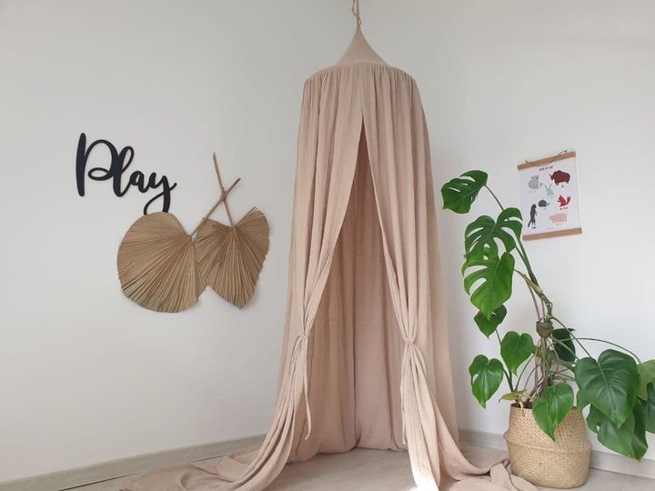 A Beige muslin canopy suspended above a cozy reading nook, perfect for escaping into a good book