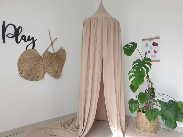 A neutral-toned muslin canopy in beige, adding a touch of rustic charm to the room&#39;s decor